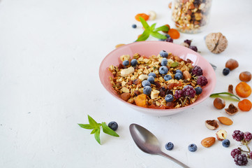 Vegetarian breakfast: homemade granola with nuts, seeds, blueberries, strawberries in a pink plate. The concept of diet, healthy eating, fitness diet. Losing weight.