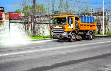 Fototapeta na wymiar Street disinfection - a sweeper washes the city's asphalt road with water jets.