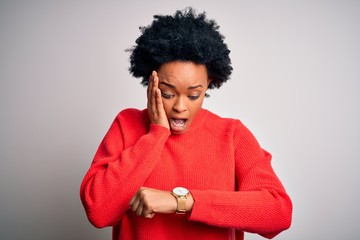 Fototapeta na wymiar Young beautiful African American afro woman with curly hair wearing red casual sweater Looking at the watch time worried, afraid of getting late