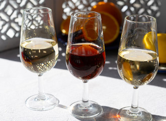 Glasses with cold dry fino and sweet cream sherry fortified wine and orange in sunlights, andalusian style interior on background