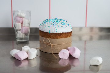 Easter cake with a white top, decorated with multi-colored sprinkles and marshmallows on kitchen...