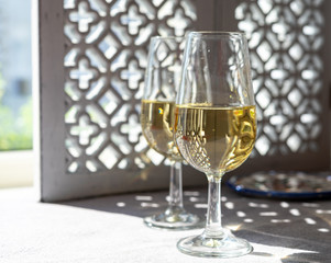 Glasses with cold fino sherry fortified wine in sunlights, andalusian style interior on background