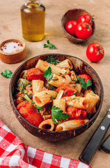 Pasta Tortiglioni with minced meat, tomato sauce and tomatoes in coconut bowl on rustic beige background