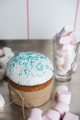 Easter cake with a white top, decorated with multi-colored sprinkles and marshmallows on kitchen table