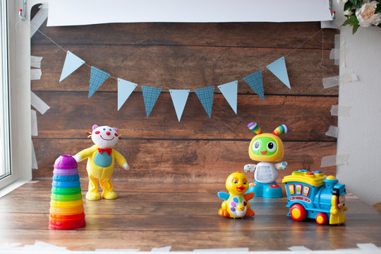 Background for one year old baby photo shoot. Paper garland on wooden backdrop with toys. For little boys and girls. 