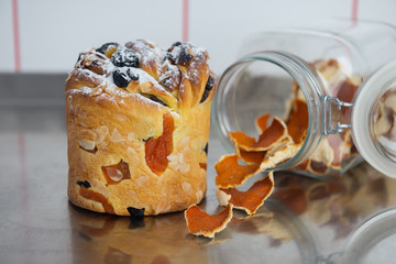 Cruffin as Easter cake decorated with raisins, dried apricots, sugar powder and a glass jar with tangerine zest on kitchen table