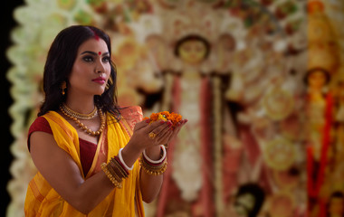 Portrait of a beautiful Married Bengali woman offering flowers , during Durga puja celebrations
