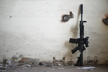 Airsoft rifle on an old wall background with copy space. - obrazy, fototapety, plakaty