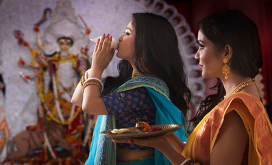 Two Bengali Married women perfoming Puja on the occasion , during Durga puja celebrations
