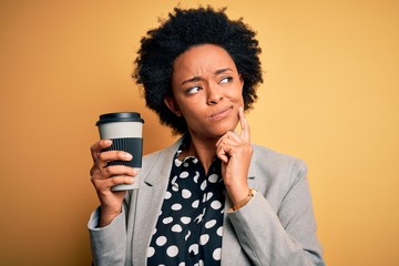 Young African American afro businesswoman with curly hair drinking cup of coffee serious face...