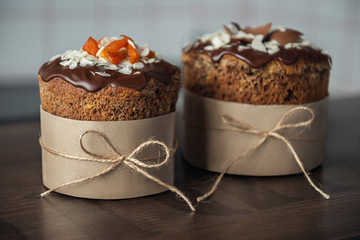 Brown Easter cakes decorated with chocolate, almond flakes and dried apricots on wooden table