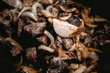 Fried with onions meat from pork in a frying pan.