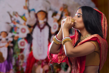 Portrait of a beautiful Bengali woman blowing conch shell at Durga puja
