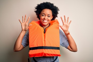 Young African American afro woman with curly hair wearing orange protection lifejacket showing and pointing up with fingers number ten while smiling confident and happy.