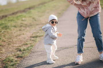 Obraz premium Happy little girl walk with her mother in park. Mom and daughter walk near promenade in Mother's Day. Cute little girl in sunglasses