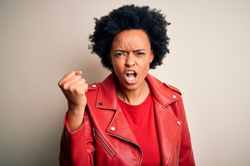 Fototapeta na wymiar Young beautiful African American afro woman with curly hair wearing casual red jacket angry and mad raising fist frustrated and furious while shouting with anger. Rage and aggressive concept.