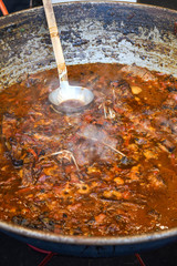 Fototapeta premium Traditional fish stew being prepared in a rustic bowl over a wood background.