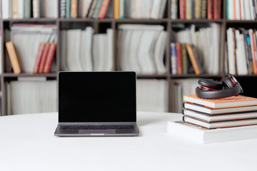 A stack of books with headphones on the background of a rack of books in the reading room of the library. Student poster