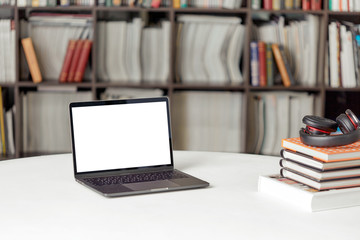A stack of books with headphones on the background of a rack of books in the reading room of the library. Student poster