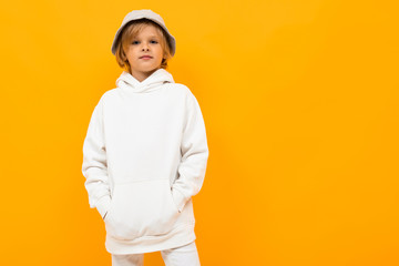 European boy with a panama in a white hoodie on a yellow background