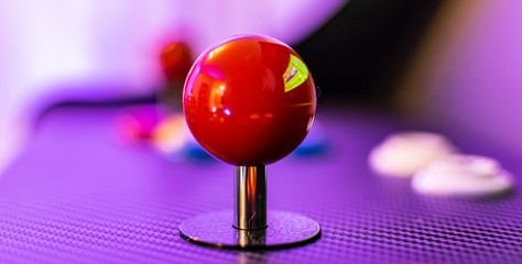 Red joystick and colorful buttons of vintage arcade game console. Close up view of old game control panel. Red sphere, ball. 