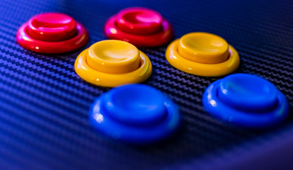 Colorful buttons of vintage arcade game console. Close up view of old game control panel. Yellow, blue and red colors. 