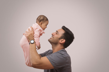 Smiling father lifting baby
