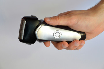 Male hand holding shaving machine on white background