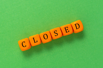 Closed inscription made from orange cubes over green background. Closed bussiness crisis.
