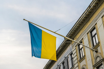 Flag of Ukraine, waving on wind, fixed to old tenement house in Lviv. 