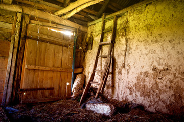Fototapeta na wymiar Old abandoned barn in the village. Inside the retro staircase leads to the attic. Horizontal frame. Photographed in Ukraine. Kiev region. Color photo.