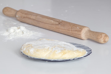 Flour and wooden rolling pin on light grey table