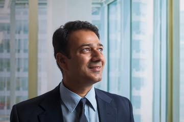 Fototapeta premium Smiling businessman in formal clothes looking away standing in office 