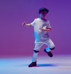 Cool young boy child dancing hip hop in the Studio against the background of neon lights. Break...