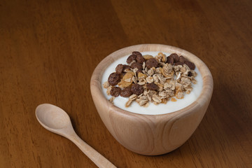 Natural homemade plain organic yogurt in wooden bowl and wood spoon on wood texture background