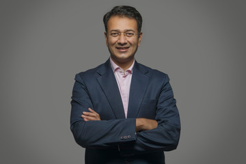 Portrait of a smiling businessman in eyeglasses with arms crossed 
