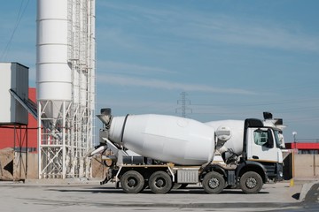 Obraz na płótnie Canvas White concrete mixers standing by a modern concrete plant.