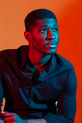 Dark neon portrait of young man wearing in shirt. Red and blue light. Technology