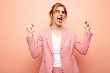 young pretty blonde woman feeling happy, positive and successful, celebrating victory, achievements...