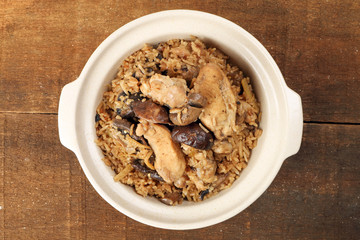 Clay pot chicken rice with mushroom in clay ceramic bowl on rustic wood table background