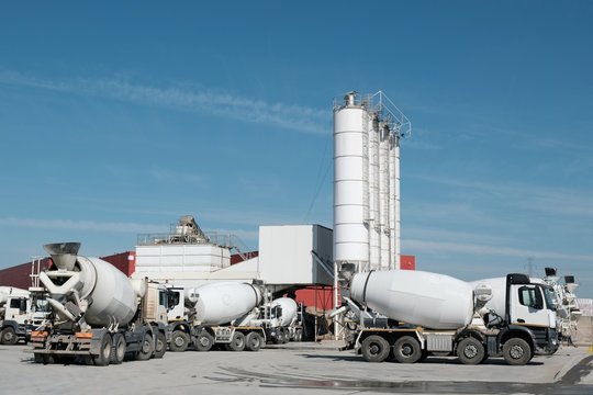 White concrete mixers standing by a modern concrete plant.