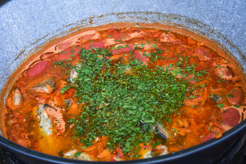 Fish stew being cooked boiling in traditional large pan