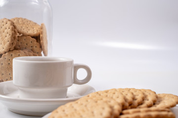 white cup of coffee with cookies on background