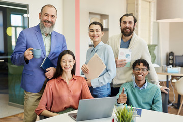 Horizontal group portrait of happy stylish business people working in modern company, looking at camera smiling