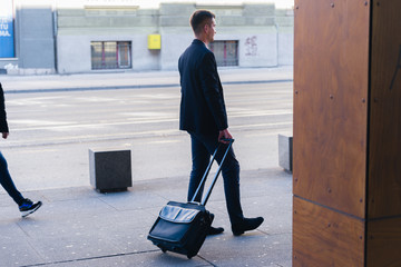 Close up photo a formal businessman dragging his suitcase, manbag, pull bag through a airport (station)