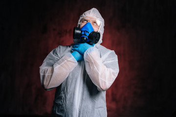 Scientist epidemiologist in protective hazmat, goggles and respirator is strangling himself with his hands. Concept of Coronavirus COVID-19 Pandemic. Studio shot on isolated dark red background.