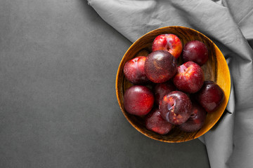Satsuma red plums clsoe up. Delicious plums in wooden plate. Copy space. © Inga