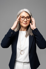 executive asian businesswoman with grey hair in eyeglasses isolated on grey