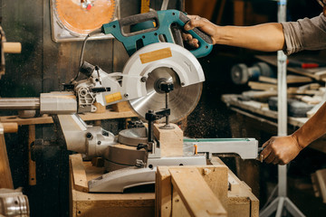Carpenter using a circular cut off saw to trim wood studs length.