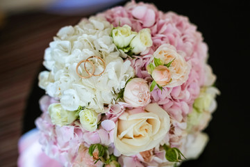 close-up of the wedding round bouquet of the bride in delicate colors pink and white, hydrangea rose , gold wedding rings
